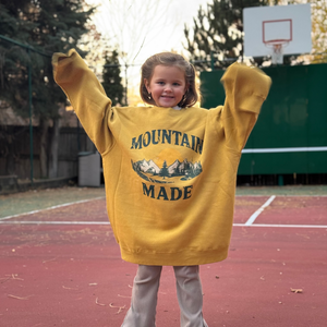 Child wearing a yellow 'Mountain Made' sweatshirt on a basketball court