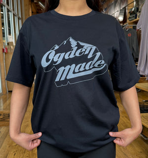 Person wearing a black t-shirt with 'Ogden Made' design in a store setting