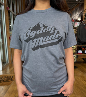 Person wearing a gray t-shirt with 'Ogden made' design in a store setting